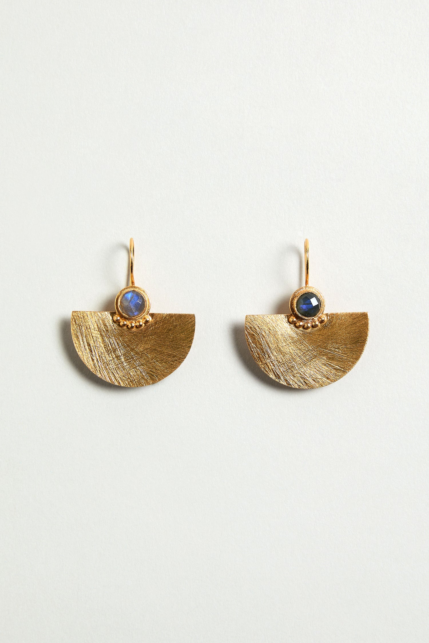 The Hand Crafted Gold Labradorite Fan Earrings feature gold fan drops with a semi-precious labradorite gemstone set above each half-circle, displayed against a neutral background.