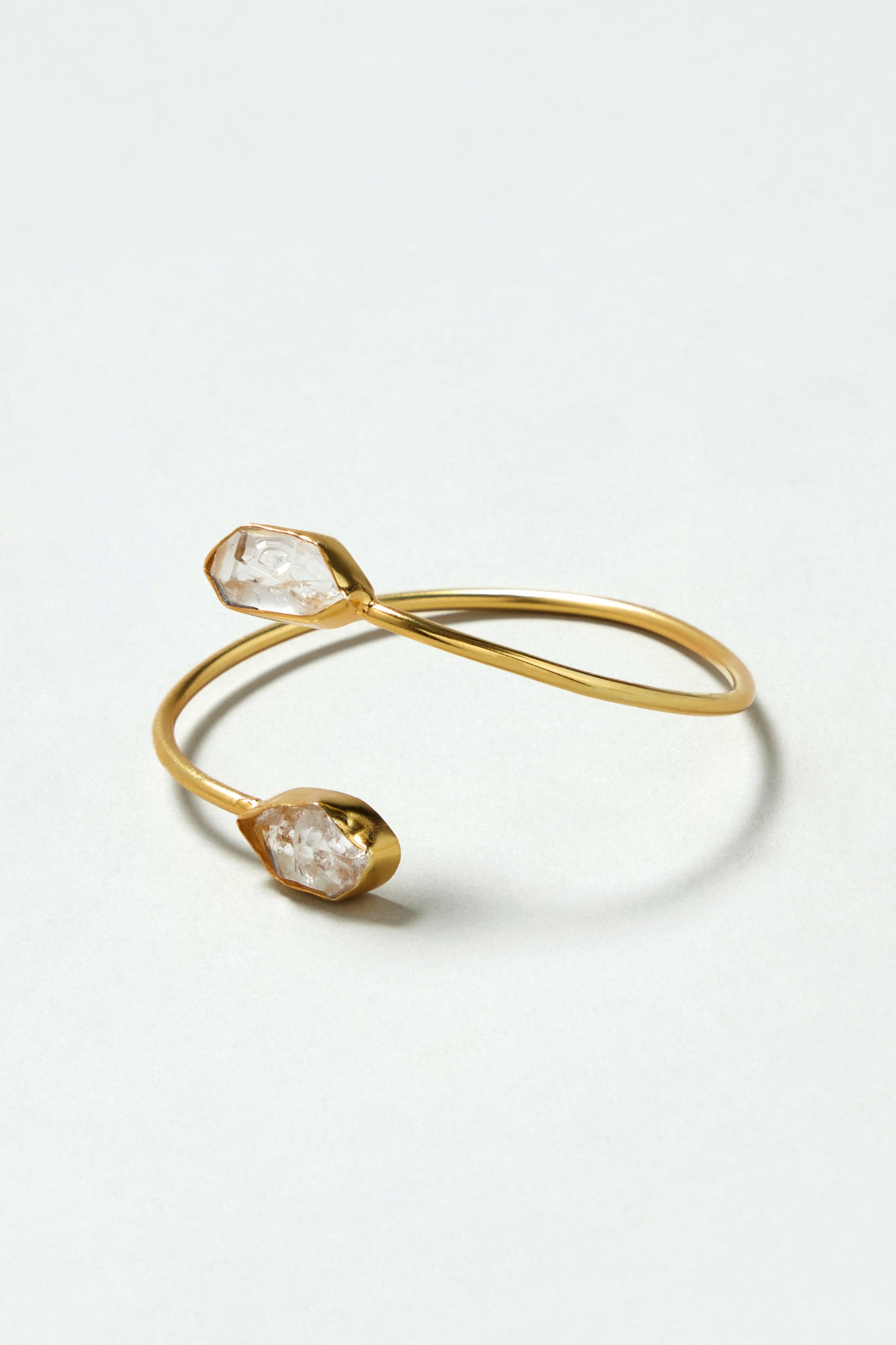The Gold Plated Quartz Herkimer Diamond Bracelet features an open cuff design with two rough Herkimer quartz gemstones set at each end, shown against a simple light background.