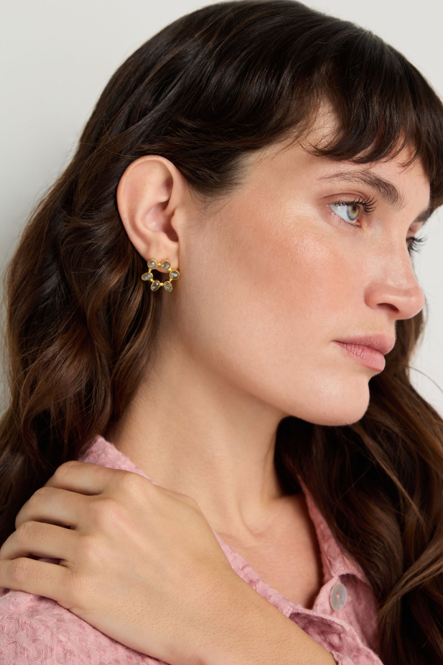 Woman with wavy brown hair, shown in profile against a plain background, wears a pink textured blouse and Hand Crafted Aqua Crackle Mini Stone Earrings.