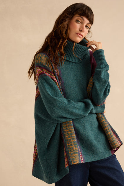 A person wearing an oversized teal Hunter Montrose Cowl Neck Sweater featuring Fair Isle patterned geometric panels.
