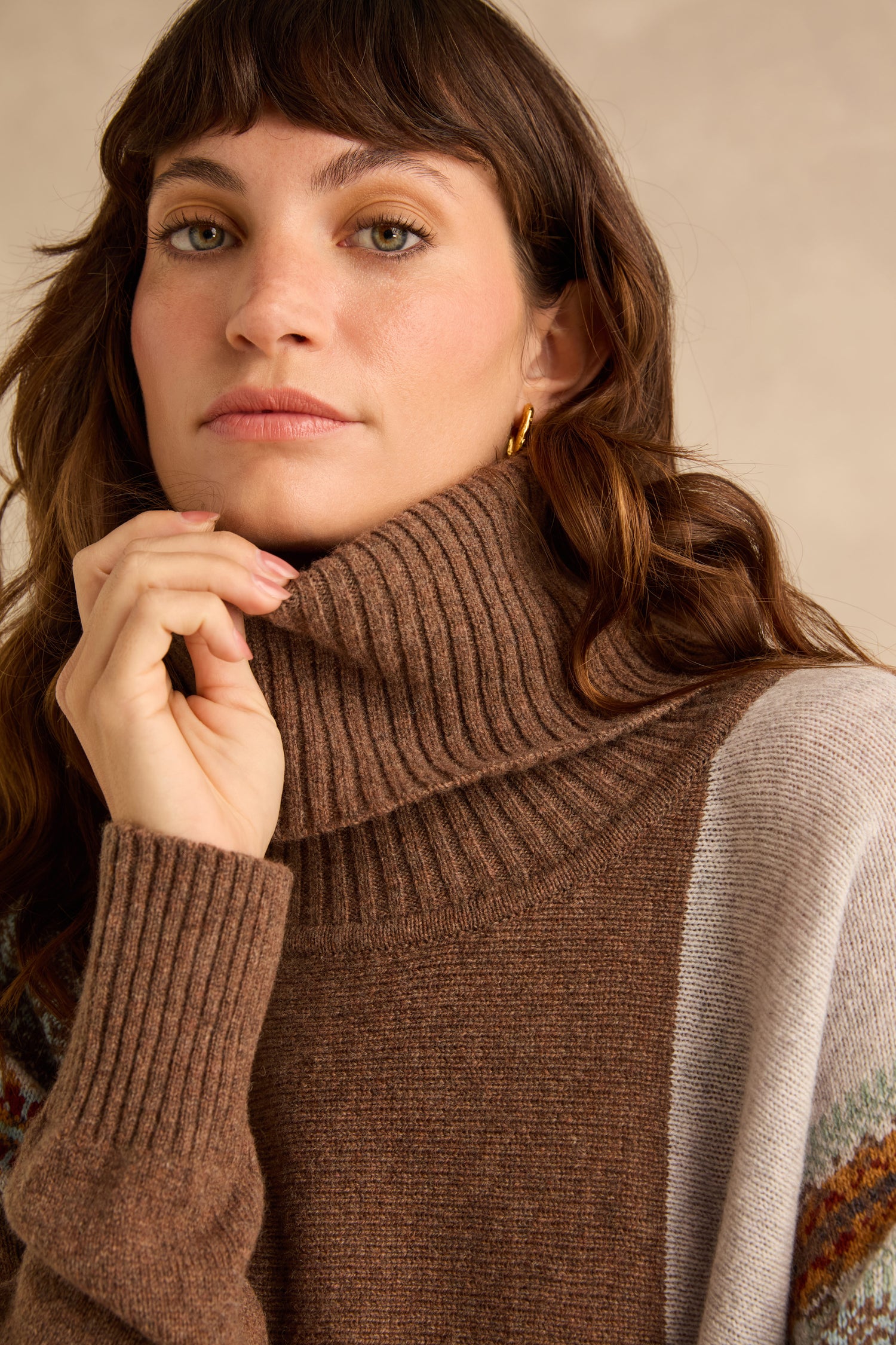 A woman wearing a brown Mushroom Montrose Cowl Neck Sweater with a ribbed cowl neck.