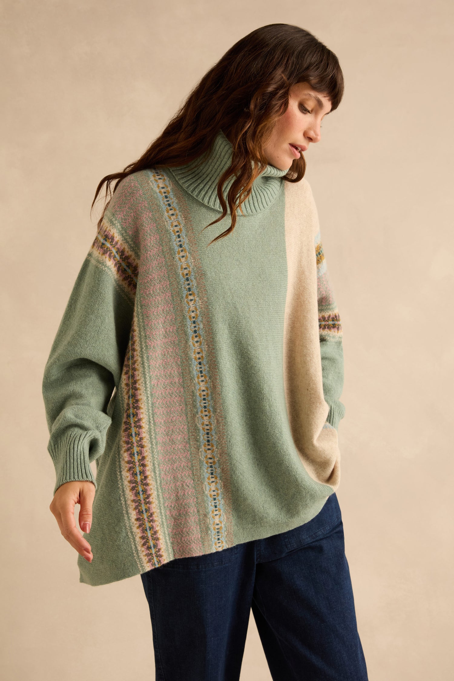 Person wearing an oversized, sage green Sage Montrose Cowl Neck Sweater featuring vertical Fair Isle patterned stripes and a solid beige panel.