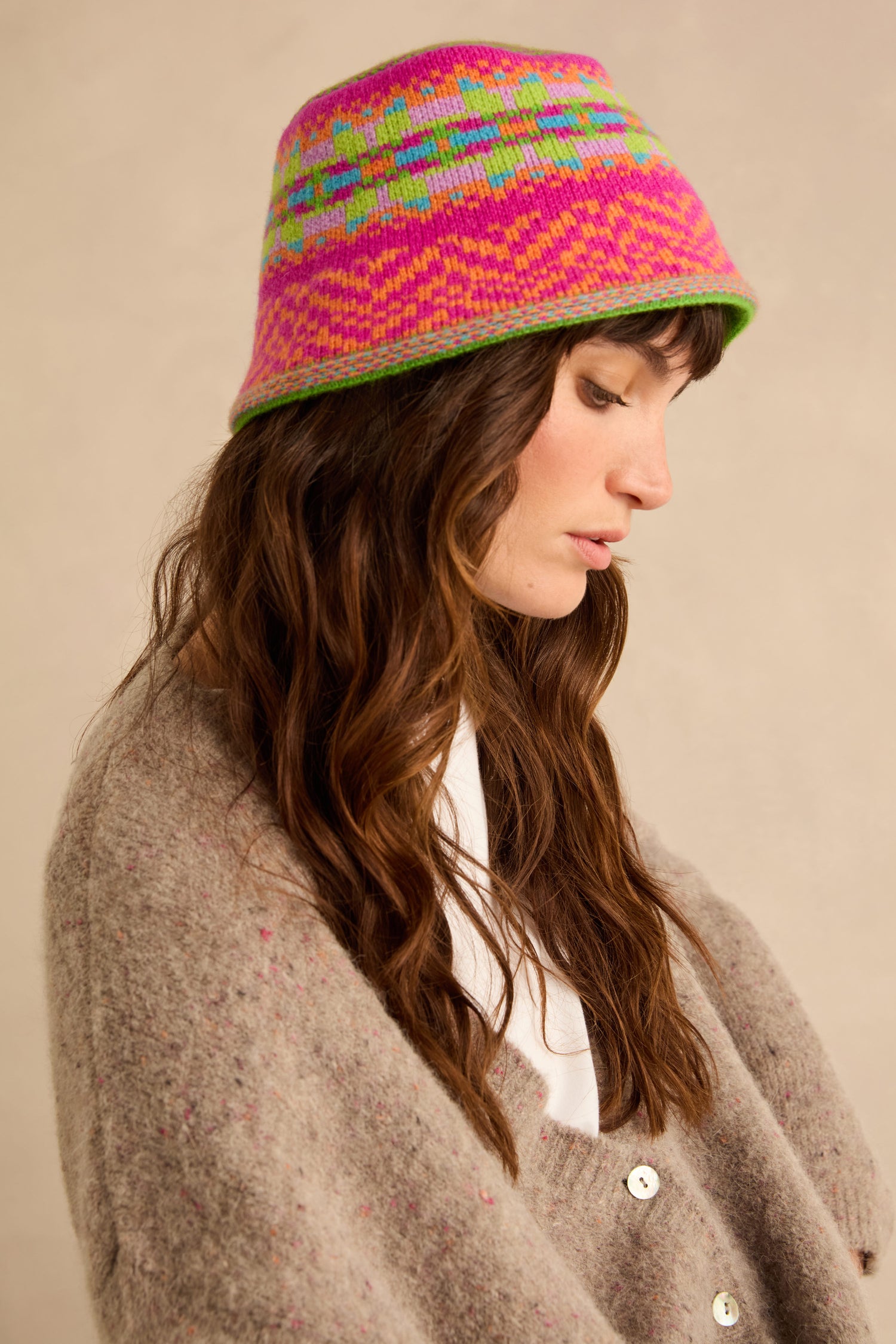 A person wearing a bright, multicoloured Stobo Graffiti Merino Bucket Hat featuring a geometric Fair Isle knit pattern.