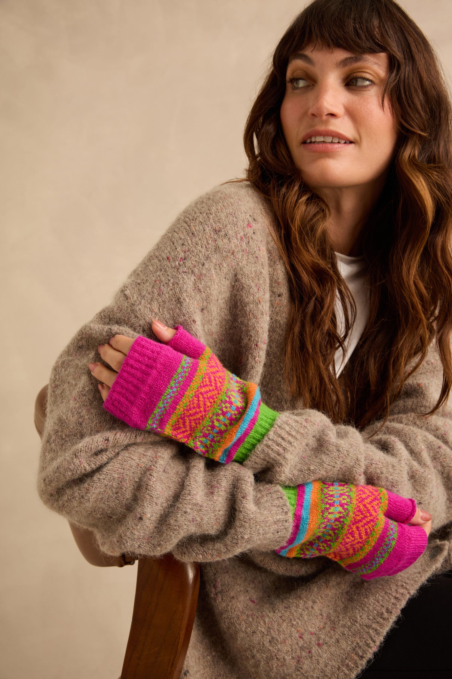 A person wearing bright pink Stobo Graffiti Merino Open Mitts with colorful geometric patterns.