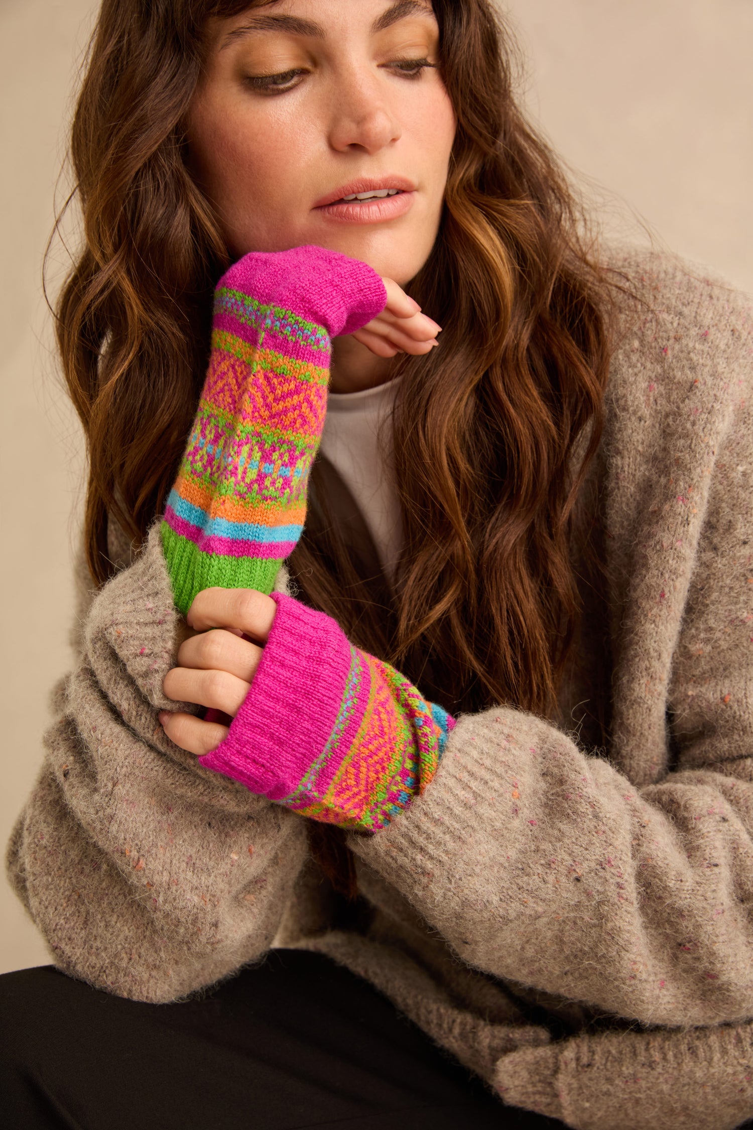 A person wearing colorful, patterned, Scottish knitwear Stobo Graffiti Merino Open Mitts that are fingerless and extend past the wrists.