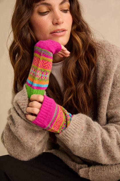 A person wearing colorful, patterned, Scottish knitwear Stobo Graffiti Merino Open Mitts that are fingerless and extend past the wrists.