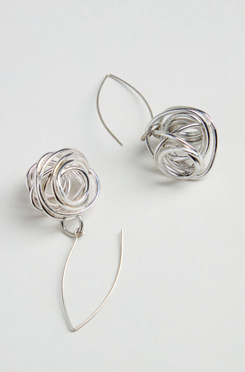 The Silver Scribble Earrings feature a unique tangled knot design with curved, thin wire hooks for a sculptural look that’s lightweight and stylish.
