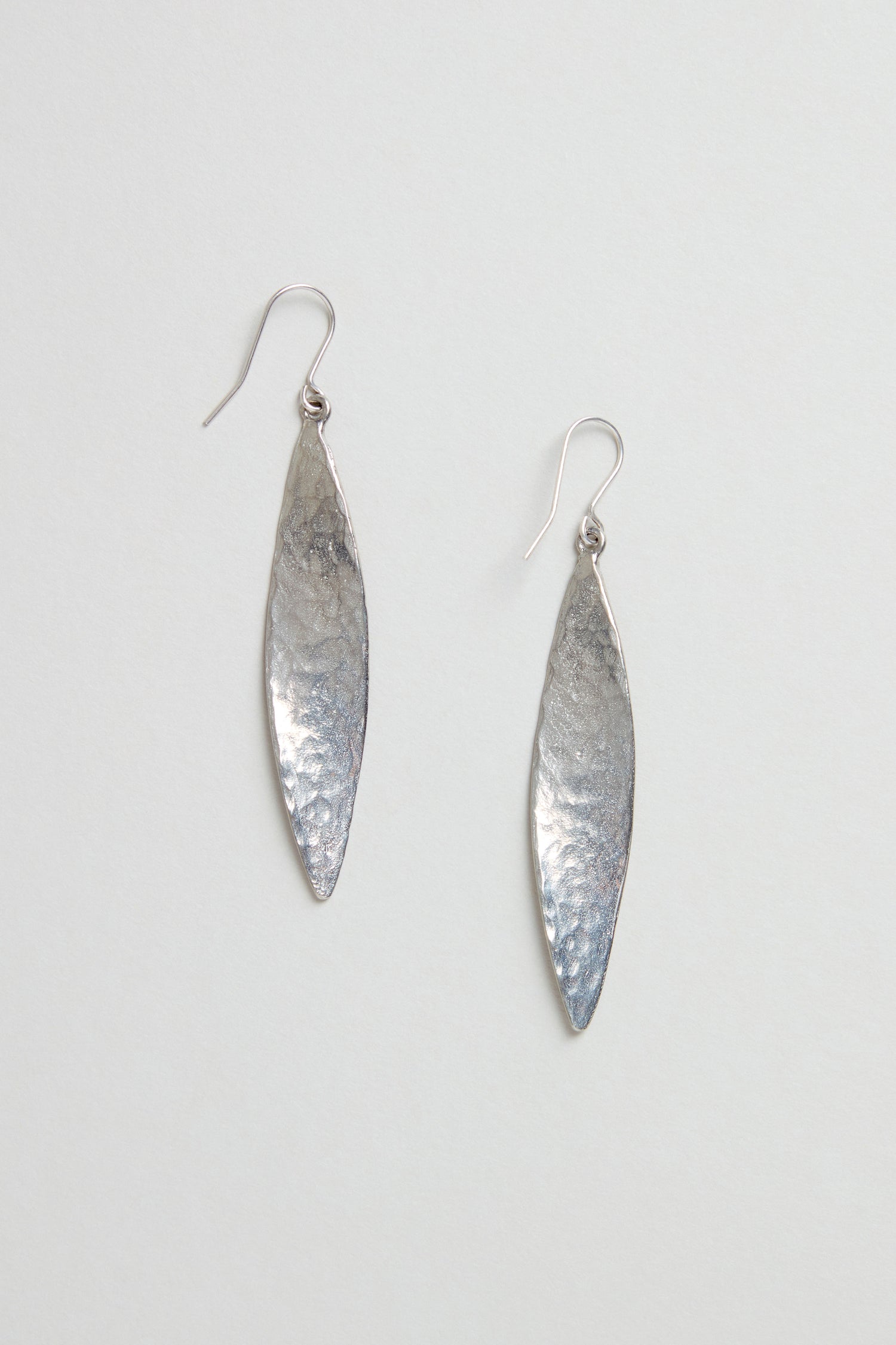Hammered Silver Leaf Earrings—long, leaf-shaped silver earrings with a textured, hammered finish—shown against a plain light background.