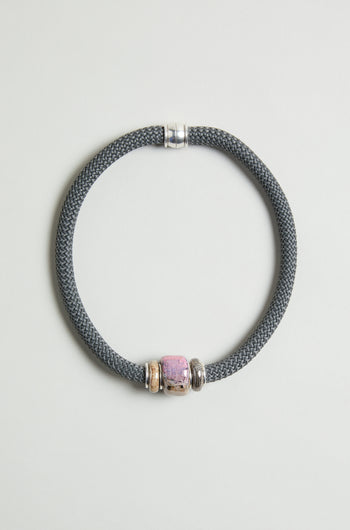 The Pink Marble Bead Short Cord Necklace features a gray braided chunky cord, silver accents, and a central pink marble bead, displayed on a light background to highlight this elegant handmade statement jewelry piece.