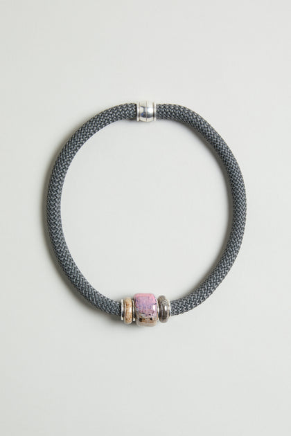 The Pink Marble Bead Short Cord Necklace features a gray braided chunky cord, silver accents, and a central pink marble bead, displayed on a light background to highlight this elegant handmade statement jewelry piece.