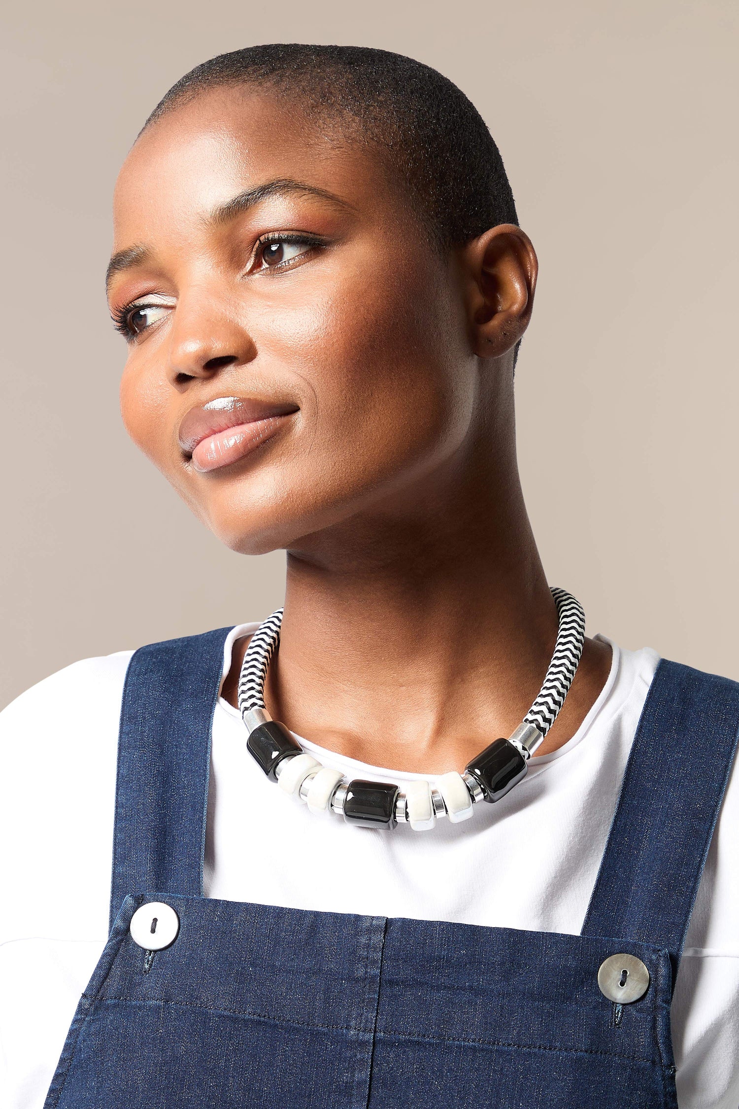 A woman wearing overalls and a Monochrome Bead Necklace.