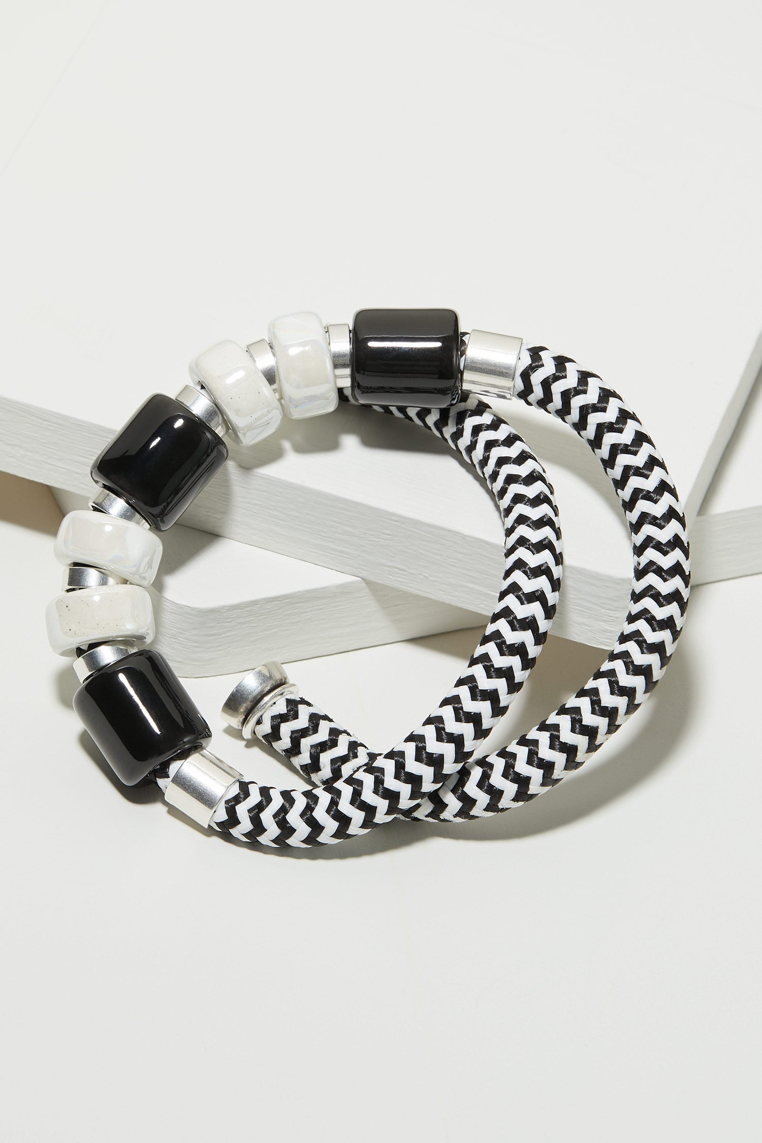 A black and white striped bracelet and a Monochrome Bead Necklace on a white surface.