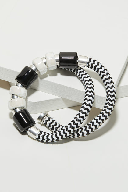 A black and white striped bracelet and a Monochrome Bead Necklace on a white surface.