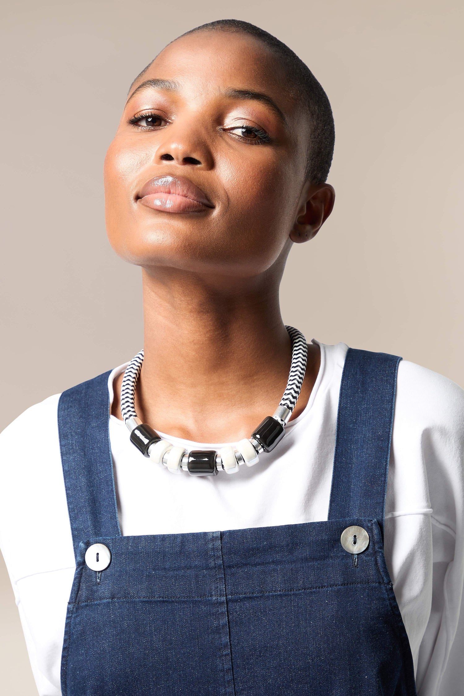 A black woman wearing overalls and a Monochrome Bead Necklace.