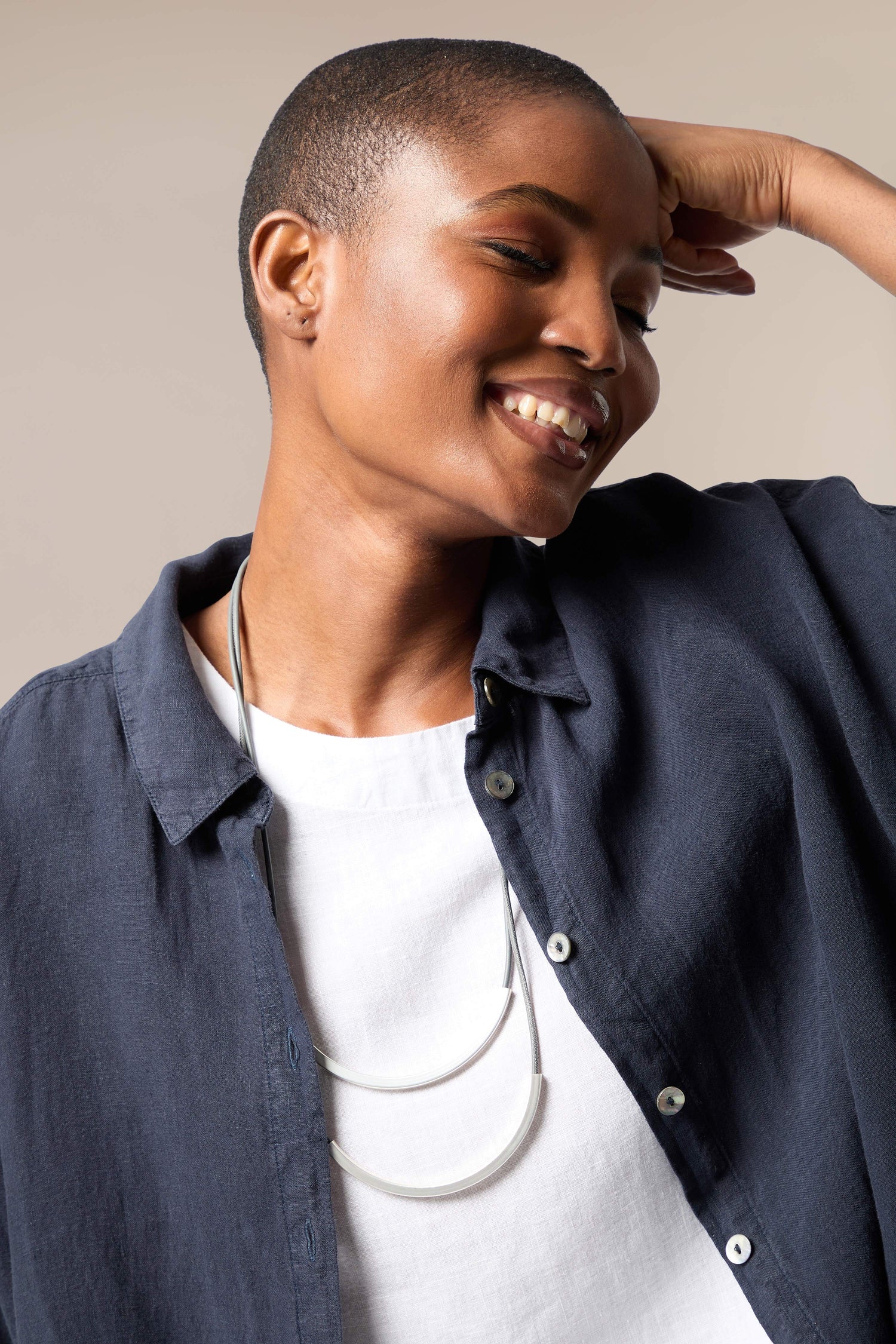 A black woman wearing a white shirt and a Double Loop Necklace from Etnika.