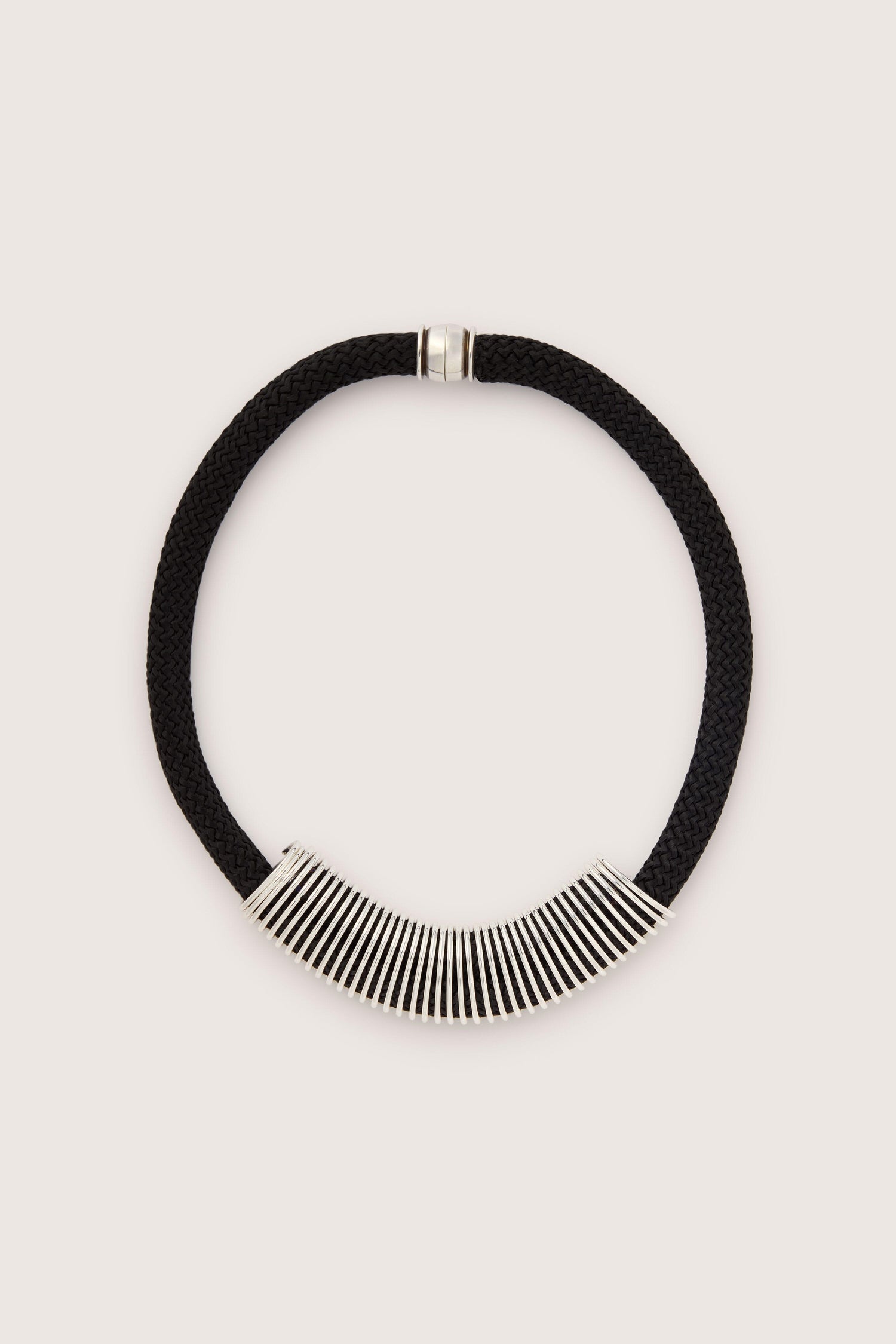 A Spring Cord Necklace with a silver magnetic closure and a silver spring pendant at the front, featuring a series of evenly spaced, elongated metal rods.