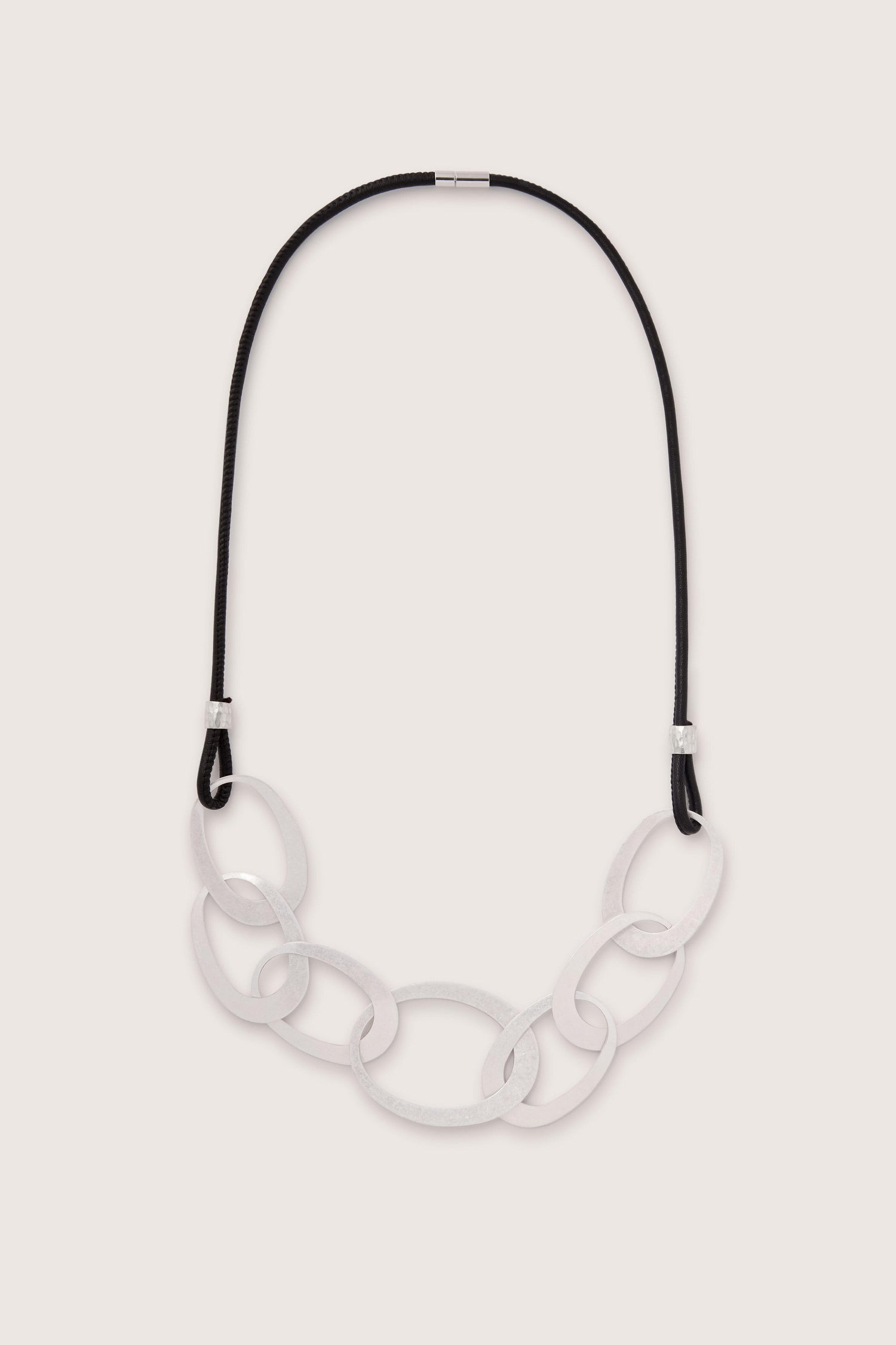 The Silver Links Leather Cord Necklace features large, interlocking oval-shaped silver links as a pendant, beautifully complemented by a durable black leather cord.