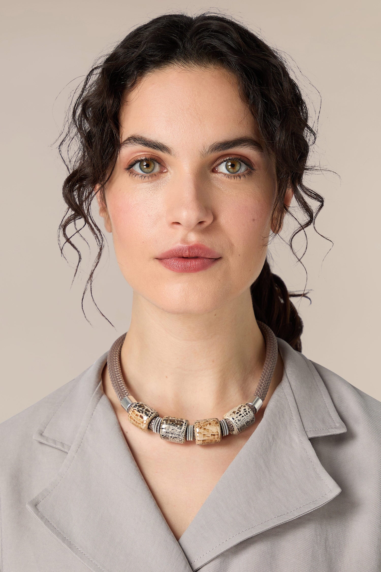 A woman wearing a grey blazer and a Ceramic Bead Cord Necklace.