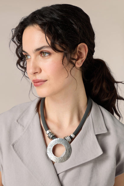 A woman wearing a Hammered Silver Circle Necklace with a grey shirt.