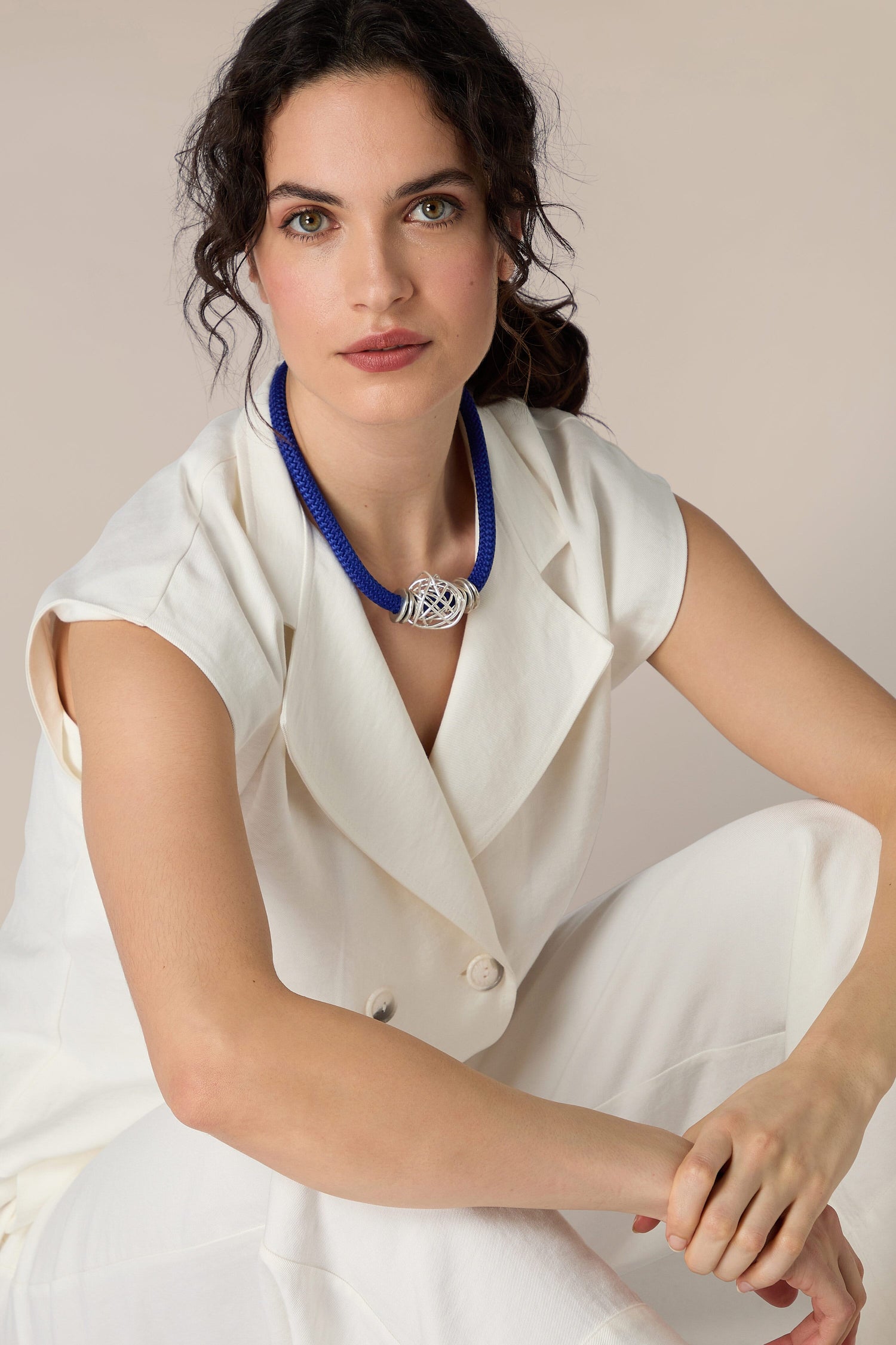 A woman wearing white pants and a Mini Scribble Cord Necklace.