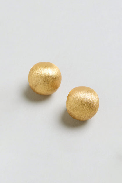 Two Brushed Sphere Earrings in a gold-colored, matte metallic finish are displayed on a simple, light background.