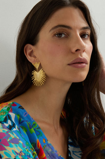 Woman wearing Gold Plated Stargazer Earrings and a vibrant floral top gazes slightly past the camera with a neutral expression.