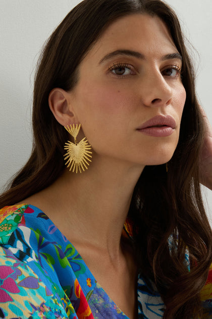 Woman wearing Gold Plated Stargazer Earrings and a vibrant floral top gazes slightly past the camera with a neutral expression.