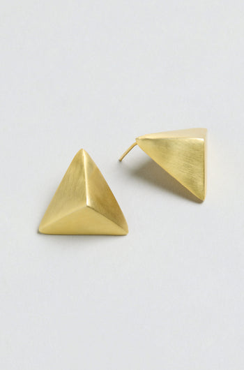 Folded Triangle Earrings crafted from recycled brass in a gold-tone geometric pyramid design, displayed on a light gray background; one earring lies flat while the other shows the back post.
