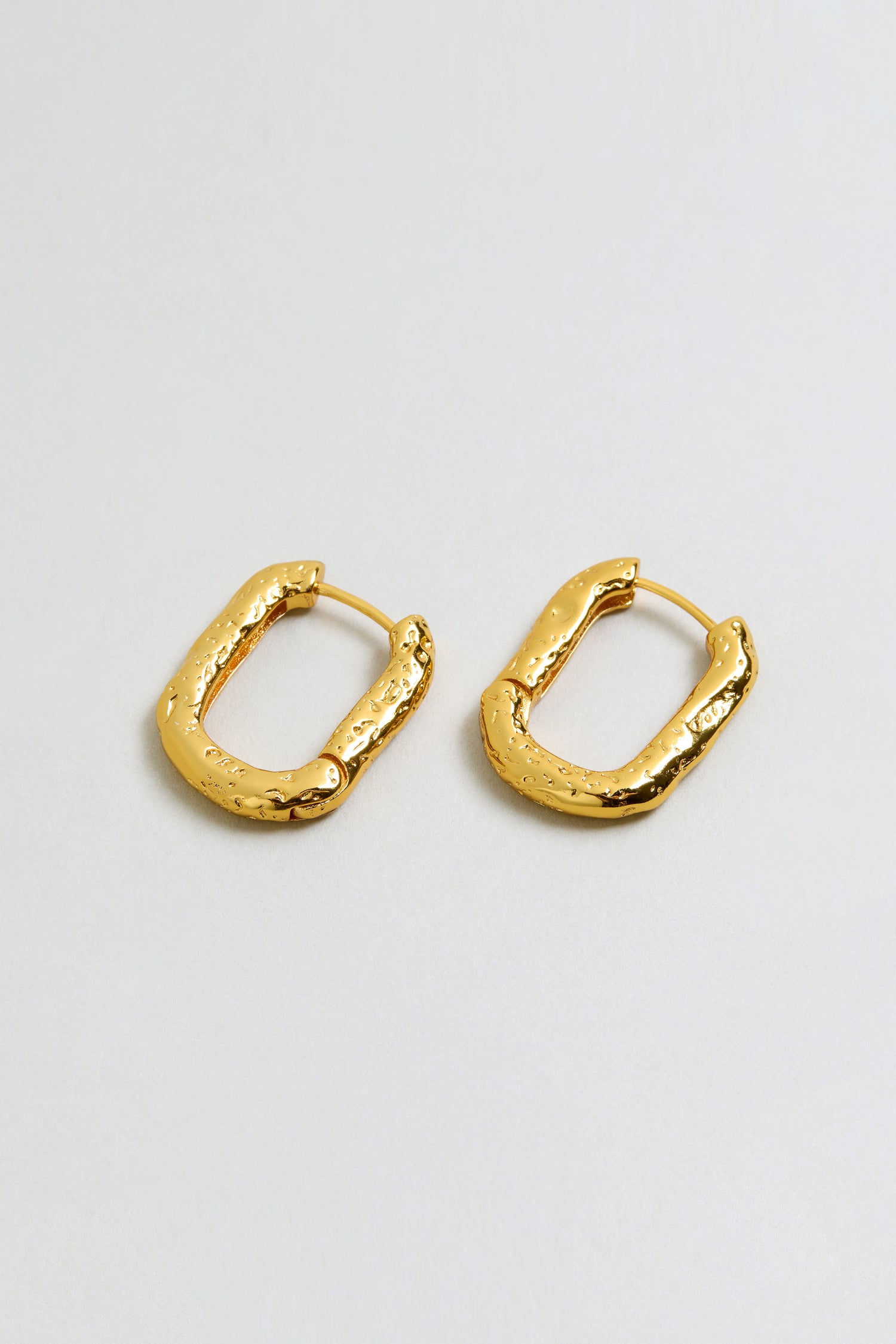 A pair of Hammered Hoop Earrings featuring irregular shapes and a textured gold-plated finish, displayed on a plain light background.