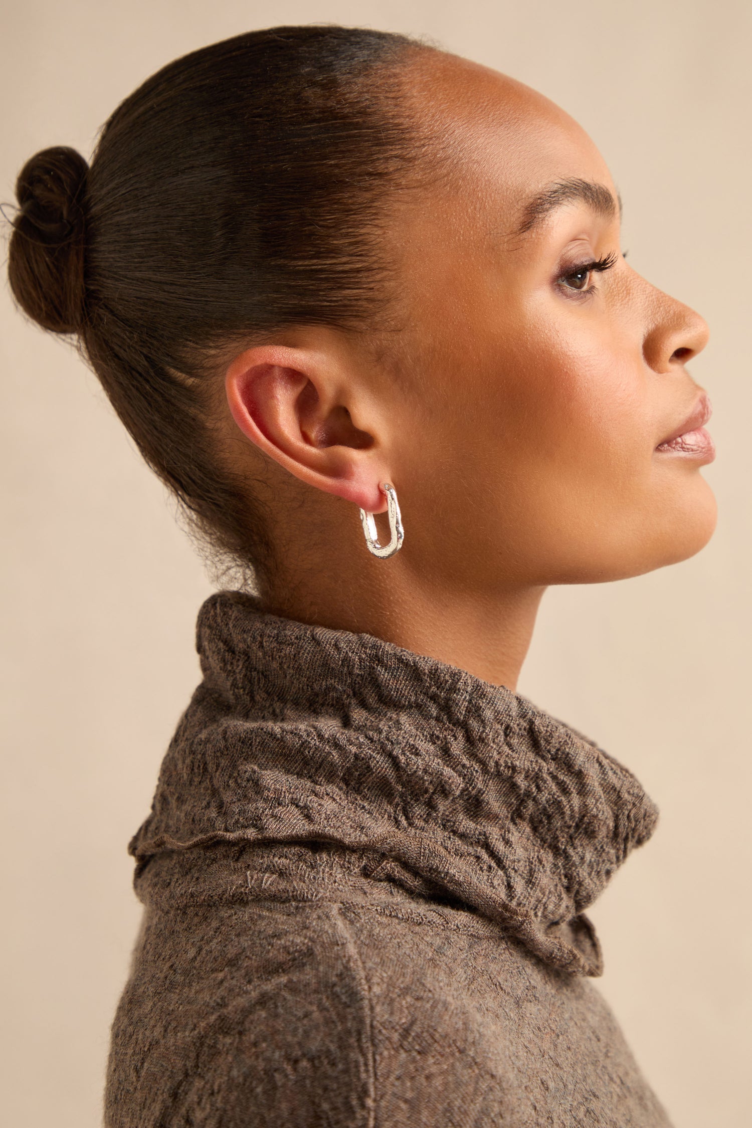 Woman in profile wearing a brown textured turtleneck and Hammered Hoop Earrings, with her hair styled in a sleek bun against a neutral background.