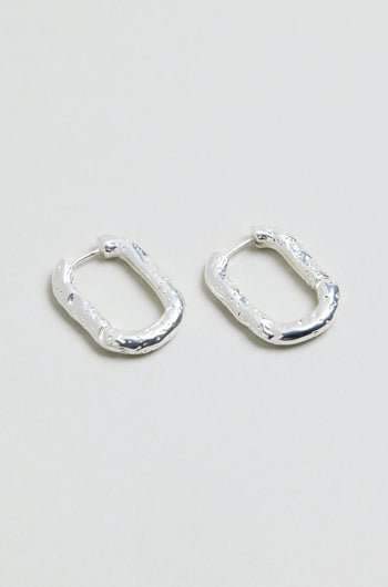 A pair of Hammered Hoop Earrings with a small, rectangular shape and textured hammered finish, displayed on a plain light gray surface.