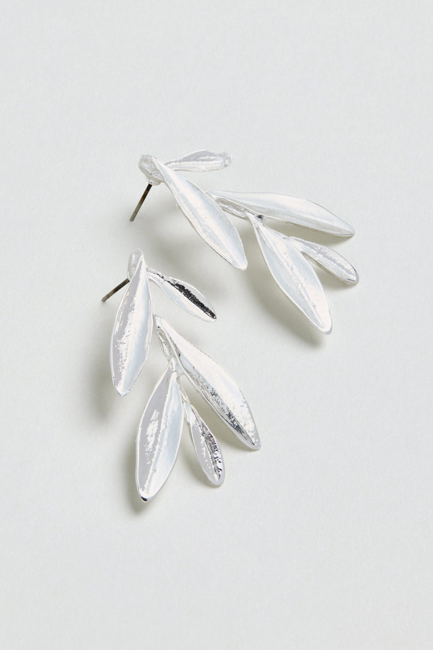 A pair of Olive Branch Earrings, silver plated and shaped like delicate leaves, displayed on a light, neutral background.