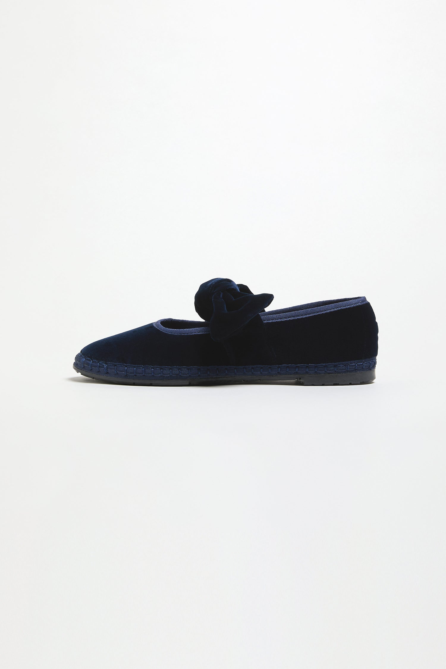 A single Navy Lyra Bow Velvet Shoe from Flabelus is shown against a plain white background, featuring the signature bow detail on top.