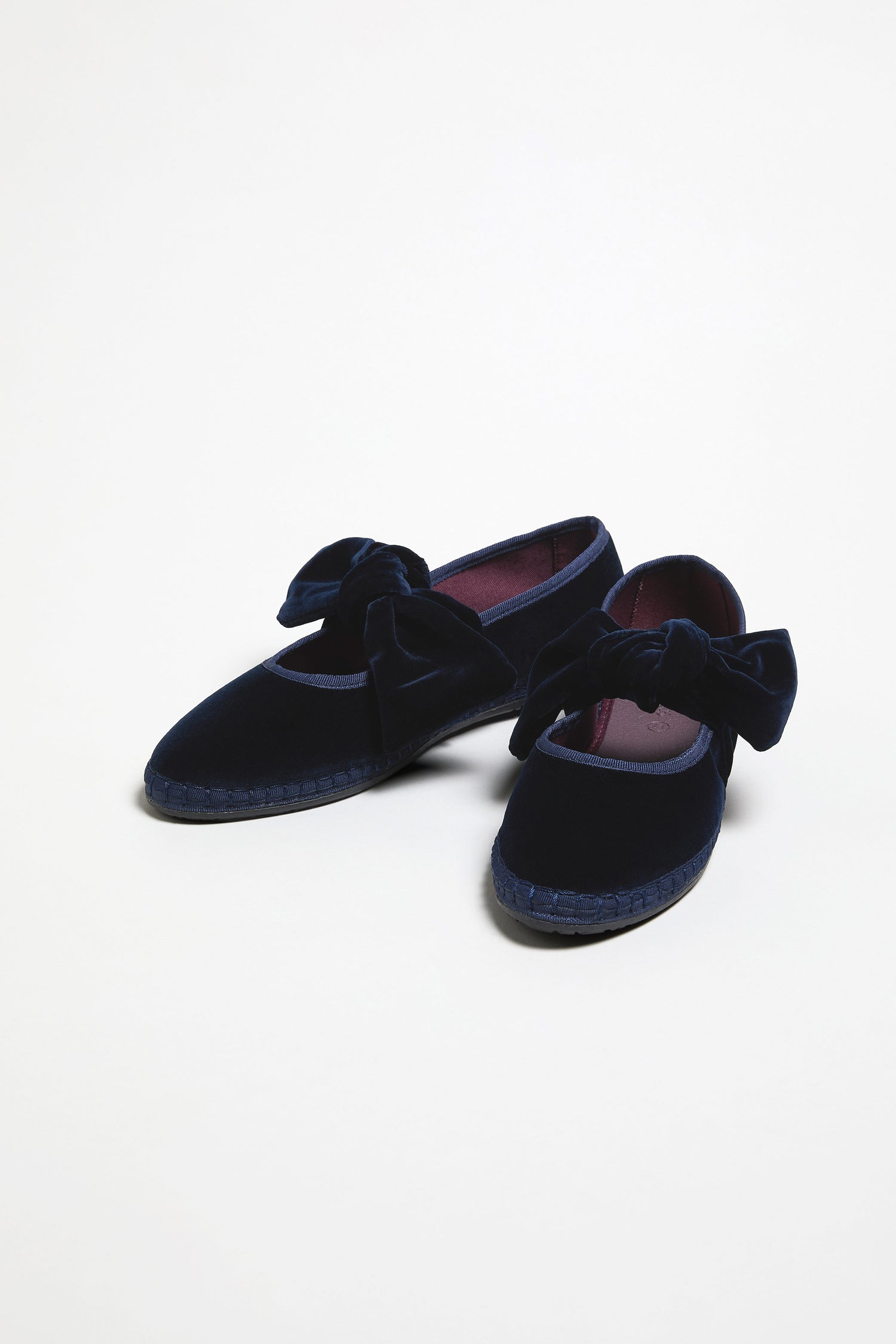 The Navy Lyra Bow Velvet Shoes feature large bow accents on top and are displayed against a plain white background.