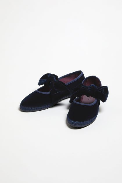 The Navy Lyra Bow Velvet Shoes feature large bow accents on top and are displayed against a plain white background.