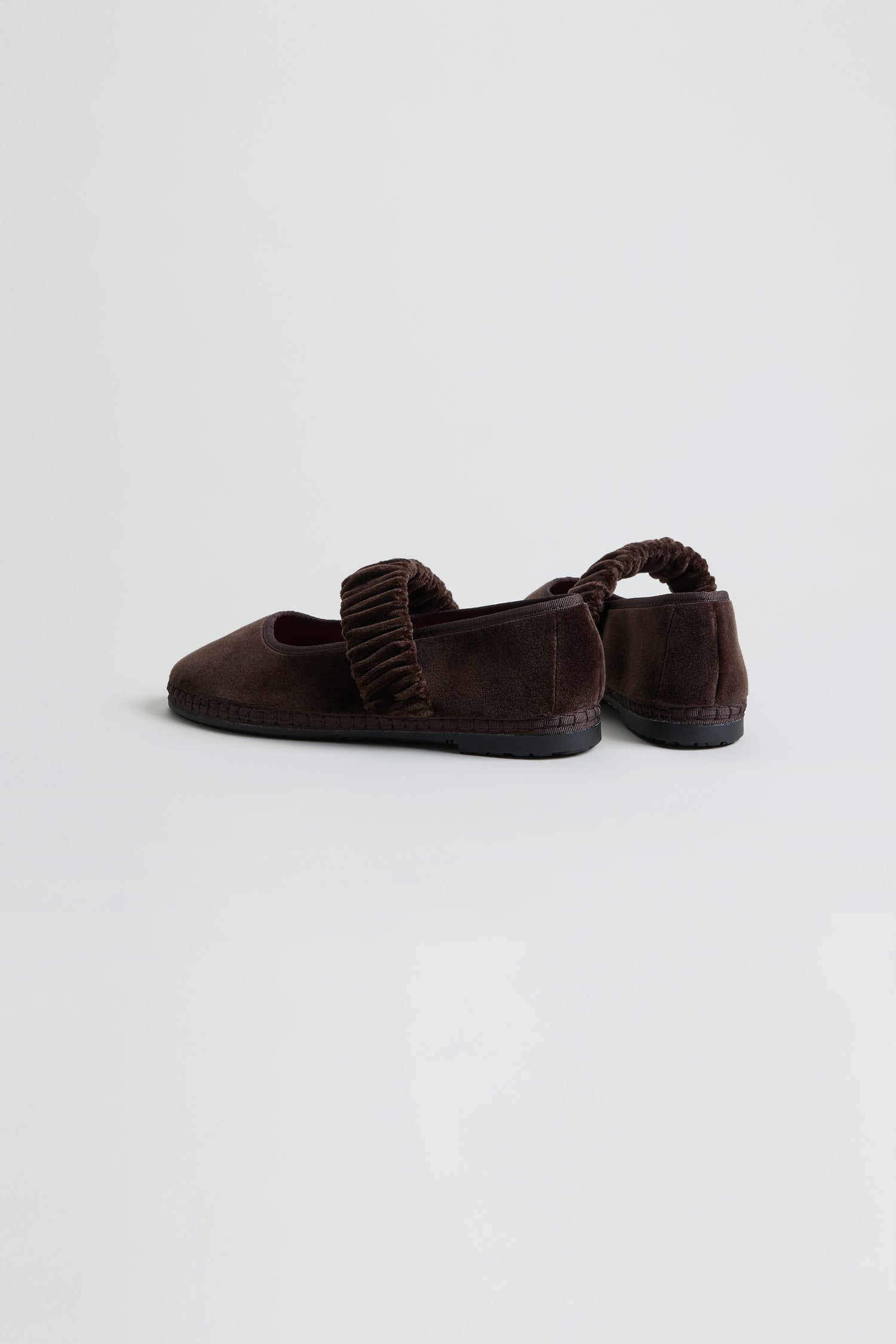 The Mafalda Truffle Velvet Shoes, handmade in Spain with dark brown velvet and ruched elastic straps, feature a recycled rubber sole and are displayed on a plain white background.