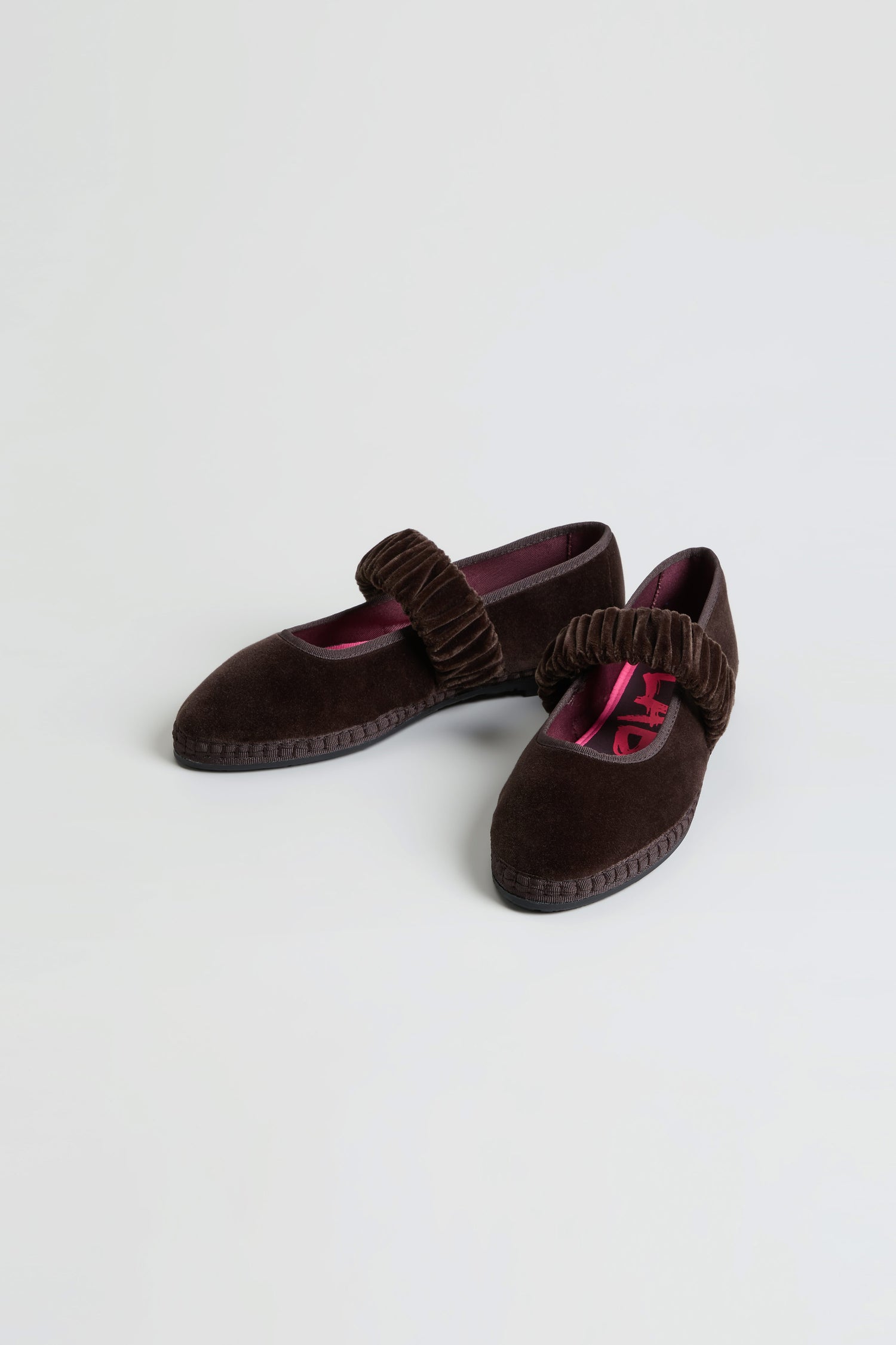 A pair of Mafalda Truffle Velvet Shoes, handmade in Spain from dark brown velvet with ruched Mary Jane straps and finished with a recycled rubber sole, displayed on a plain white background.