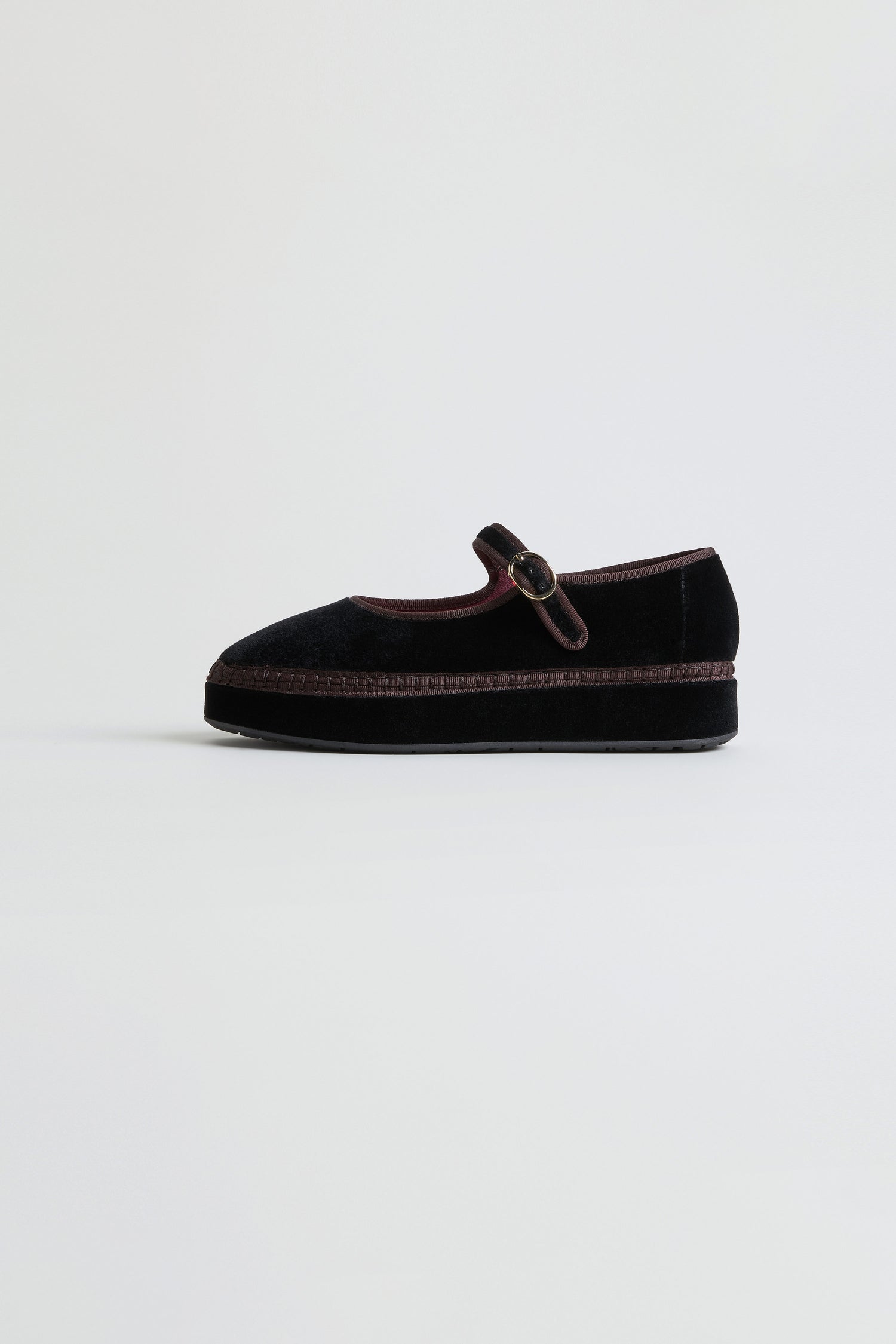 A pair of Black Velvet Platform Mary Jane Shoes with a thick sole and buckle strap is displayed against a plain light background. These handmade shoes effortlessly blend classic charm with modern style, making them the perfect choice for those seeking elegant footwear.