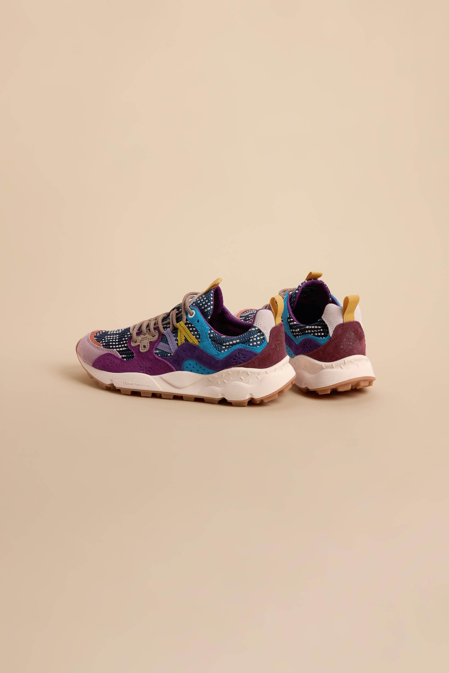 A pair of Yamano 3 Katsuo Sashi Trainers, featuring vibrant purple, blue, and yellow accents, are placed on a plain beige background.