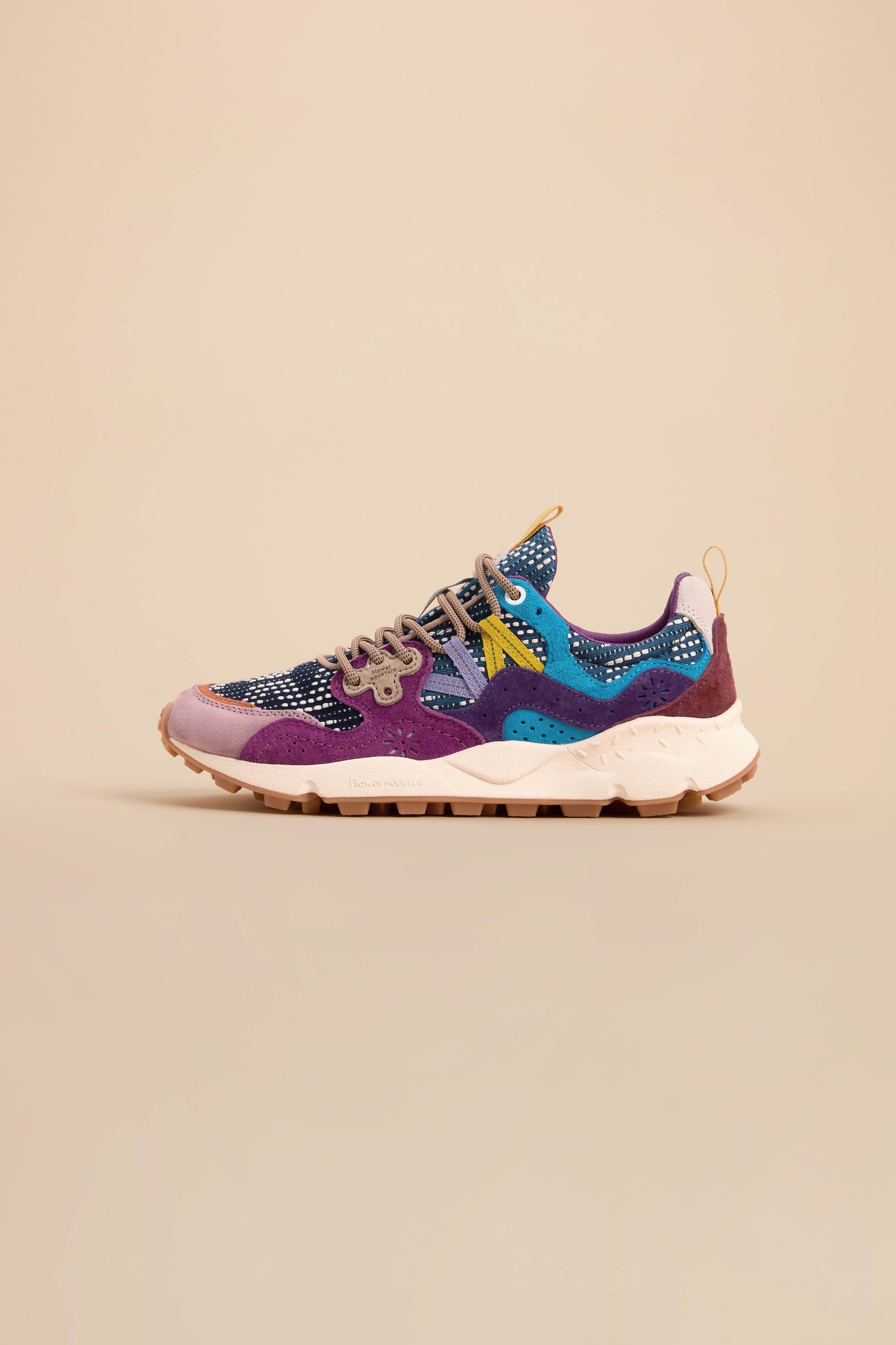 The Yamano 3 Katsuo Sashi Trainers are multicolored sneakers with a textured sole, showcasing purple, blue, and black patterns and distinctive trekking laces, displayed on a plain beige background.