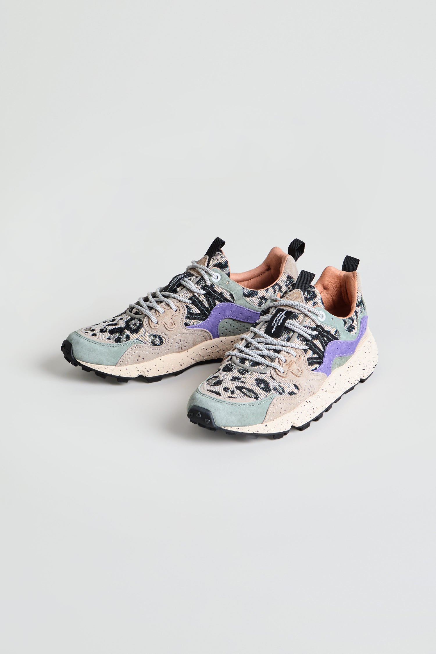 The Yamano 3 Leopard Print Trainers are a pair of trainers featuring pastel green and beige panels, purple accents, speckled chunky soles, and gray laces, displayed on a plain light background.