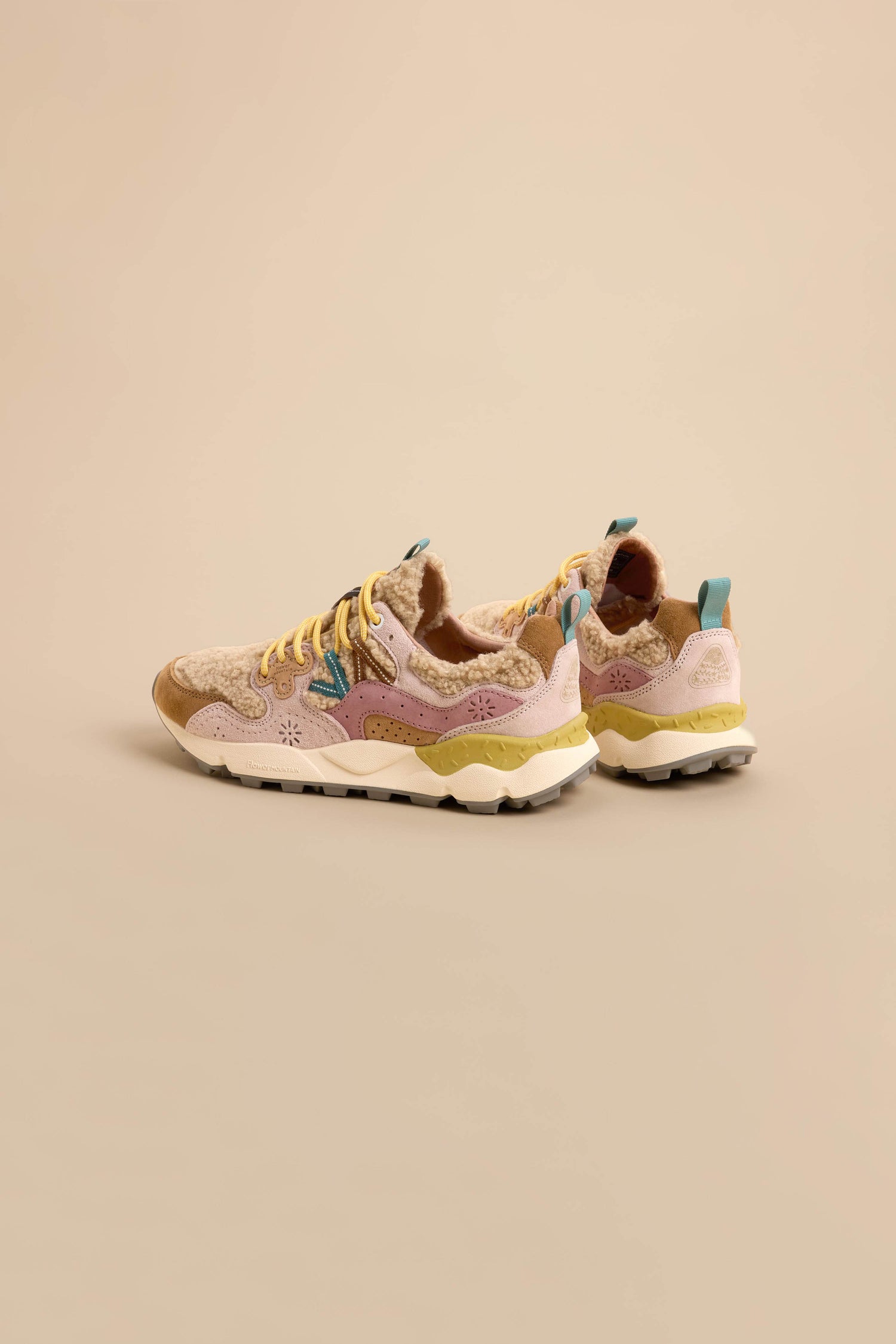 A pair of Yamano 3 Teddy Trainers in beige suede, featuring yellow laces, pink and blue accents, and white soles, are positioned on a neutral background.