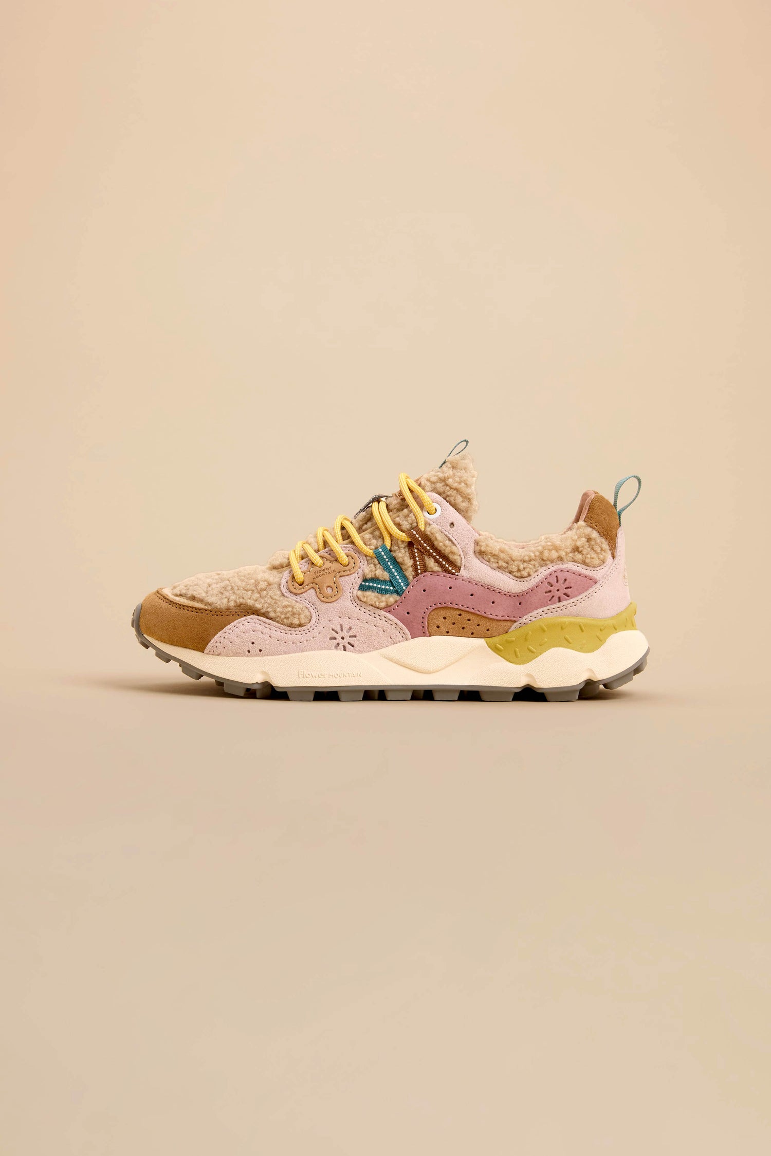 The Yamano 3 Teddy Trainer, featuring multicolored accents in pink, tan, and yellow, fuzzy lining, suede panels, and a chunky sole, is displayed on a neutral beige background.