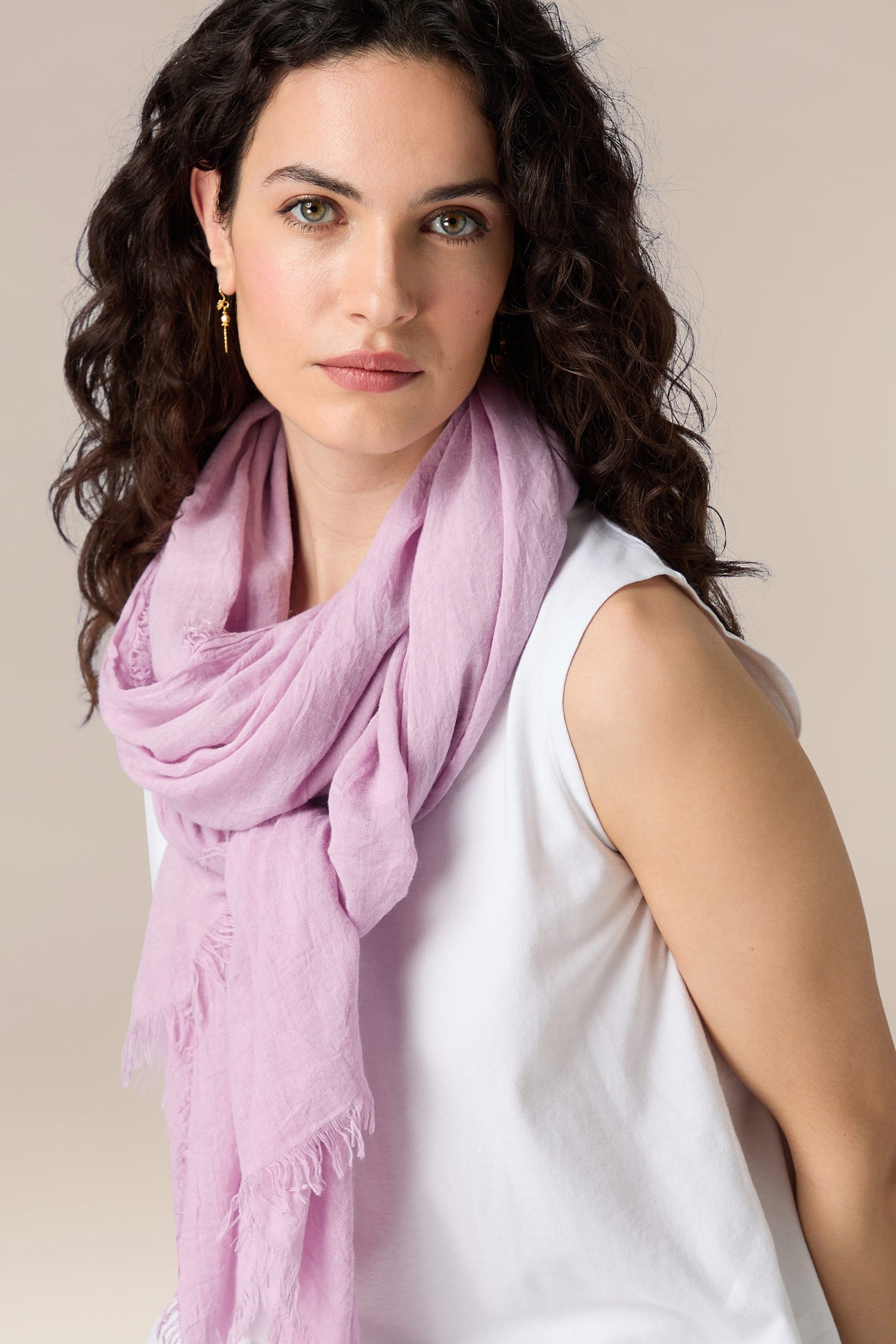 A woman with curly hair wearing a white top and a light purple Soft Fringe Scarf.