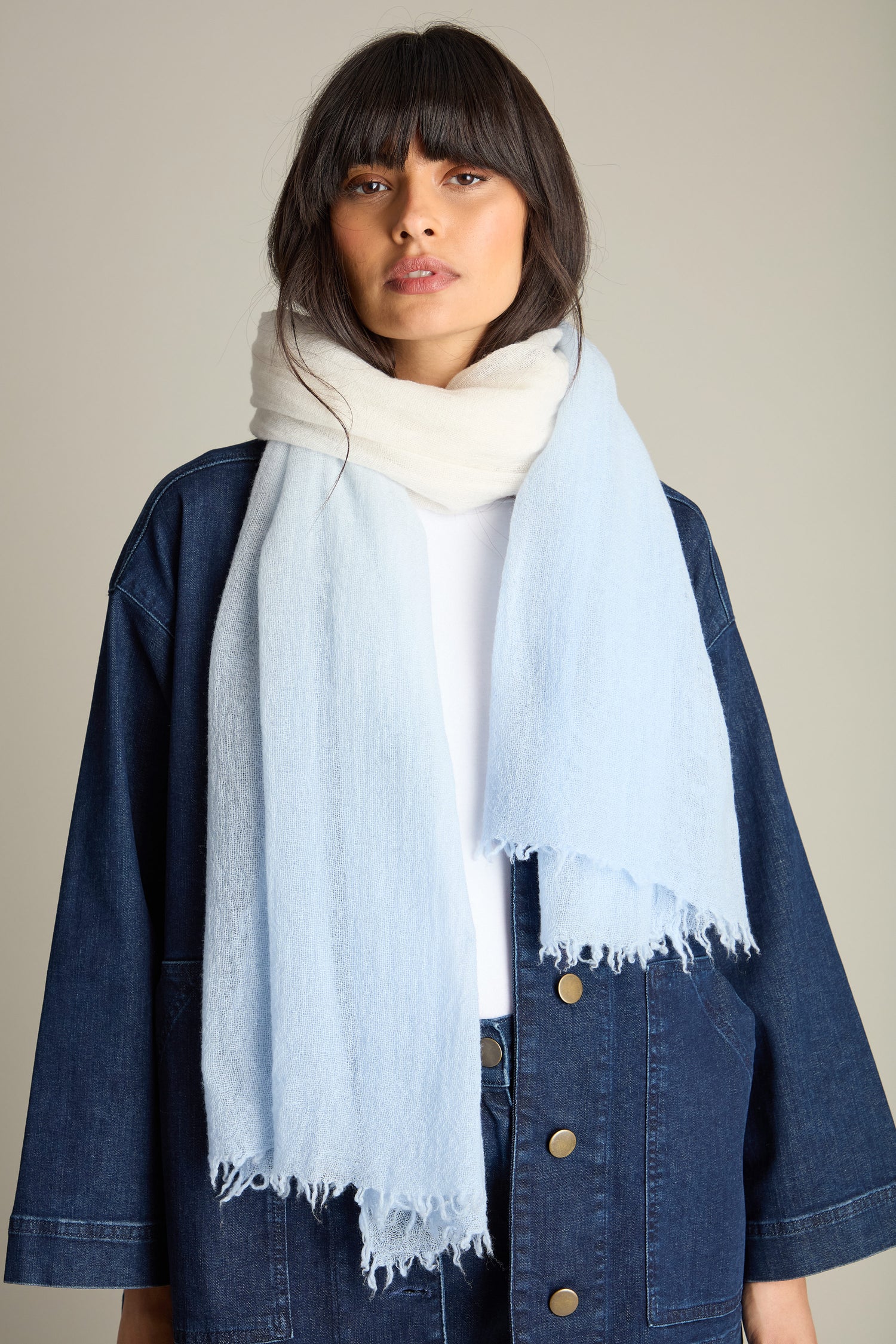 A person with long, dark hair wearing a denim jacket, white shirt, and a large Ombre Wool Scarf (Product Name: Ombre Wool Scarf) stands against a plain background.