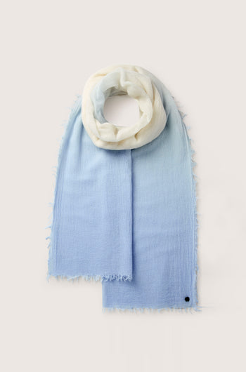 The Ombre Wool Scarf is a versatile accessory with a luxurious blend, showcasing a gradient design from white to light blue. It features fringed edges and is adorned with a small black button near the corner, making it perfect for any occasion.