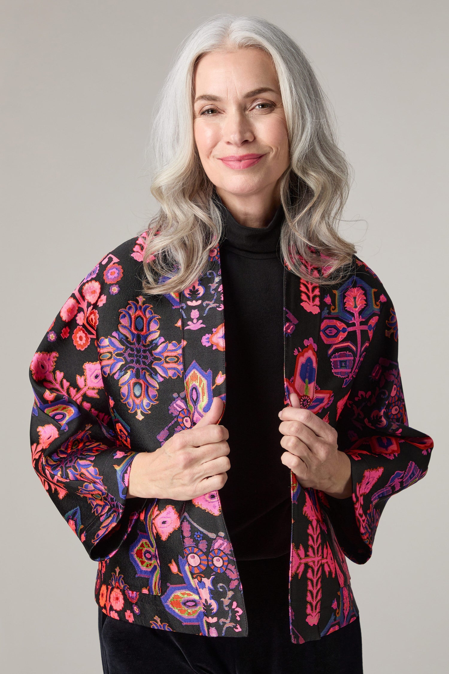 An older woman wearing a black and pink Jacquard Aztec Floral jacket.