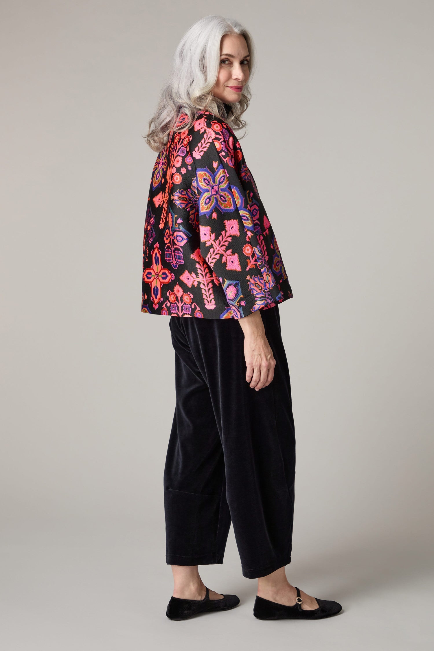 A woman making a bold statement with her Jacquard Aztec Floral Jacket, paired with black trousers.