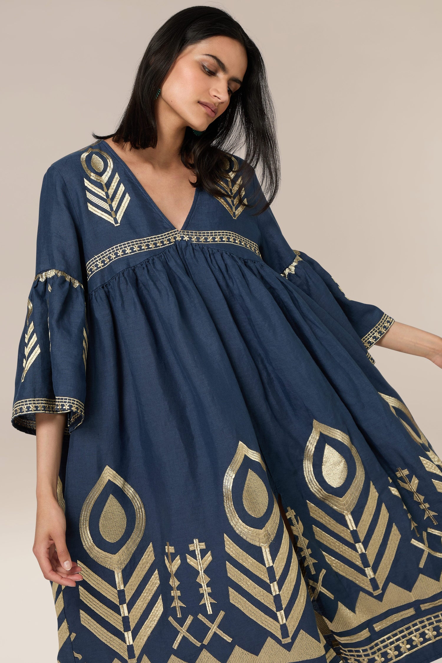 A woman wearing the Feathers Linen Midi Dress stands against a beige background.