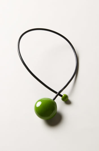 The Moss Handmade Ceramic Bead Necklace features a black choker with a large glossy green bead and a smaller green bead, reflecting elegant French design, shown against a plain white background.